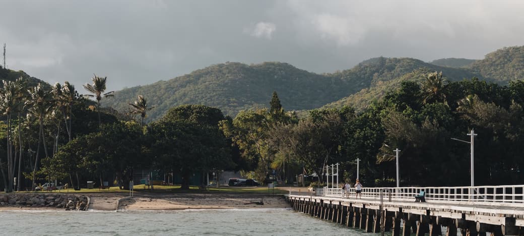 The Far North Queensland coastline near Cairns, with a jetty running out over the water and rainforest ranges behind