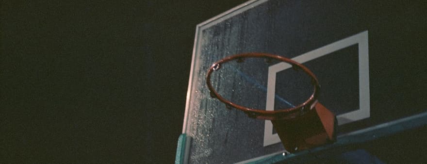 An outdoor basketball ring and backboard at dusk